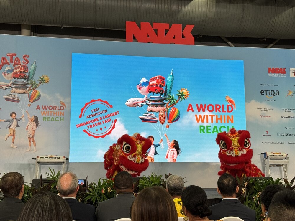 Two lion dance performers mid-routine on stage in front of a screen reading A World Within Reach