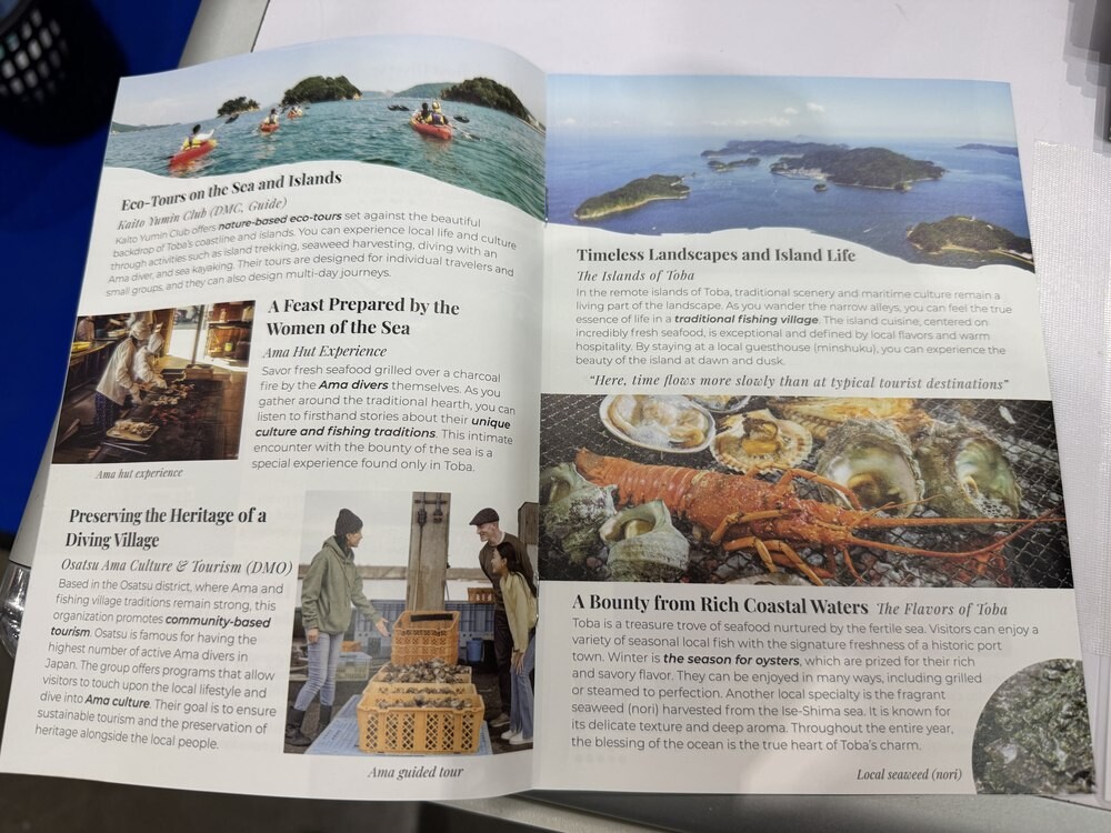 Held Japan travel brochure open to pages on eco-tours, Ama pearl-diver seafood experiences and coastal scenery around Toba in Mie Prefecture