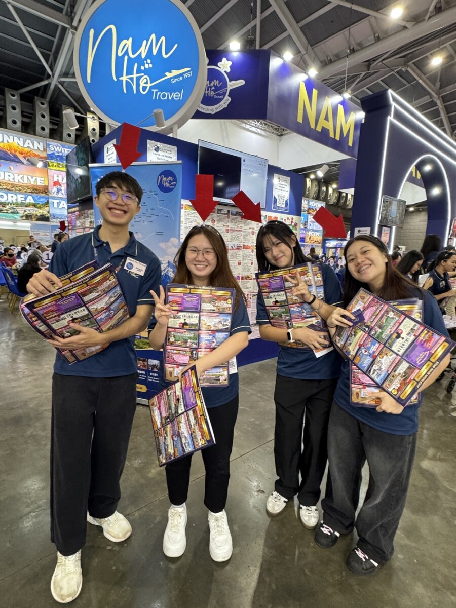 Four young Nam Ho Travel staff holding Star Tour Highlight brochures with red directional arrow signage lit up behind them