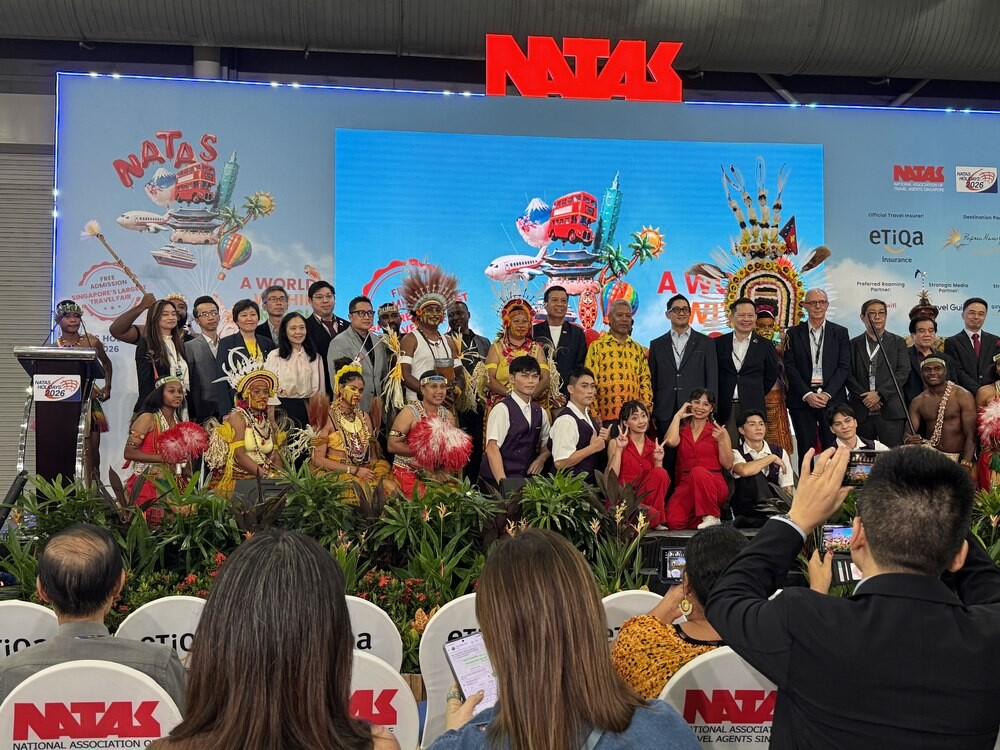 Large group photo on stage combining dignitaries in suits and batik, Papua New Guinea performers in feathered headdresses, and the Taiwan Acrobatic Troupe in red and purple costumes