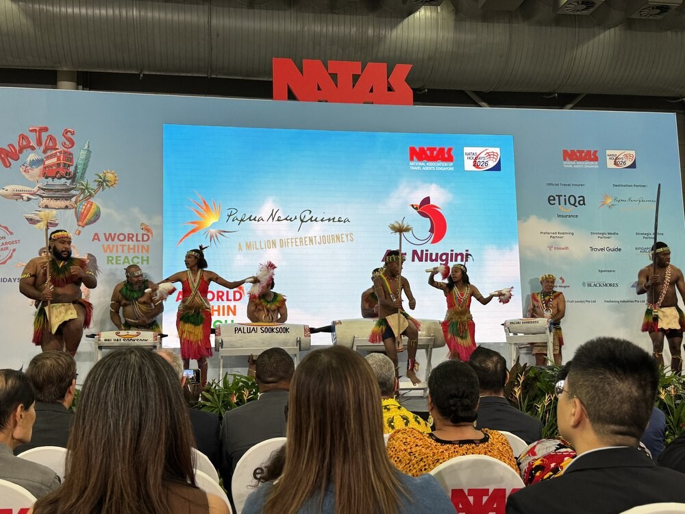 Papua New Guinea performers dancing with garamut drums on stage, screen reading Papua New Guinea A Million Different Journeys