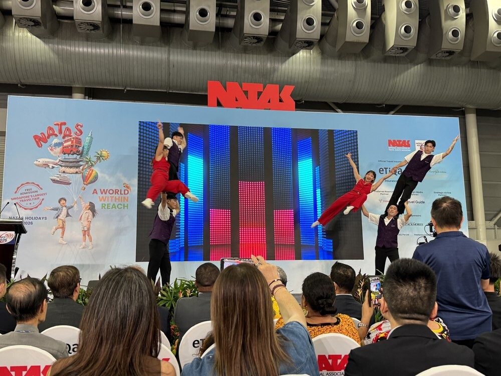 Taiwan Acrobatic Troupe performers airborne mid-toss during a stage act, with a colourful LED backdrop