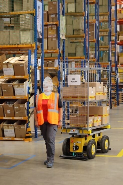 An EffiBOT autonomous trolley carrying boxes as it follows a worker through a warehouse aisle