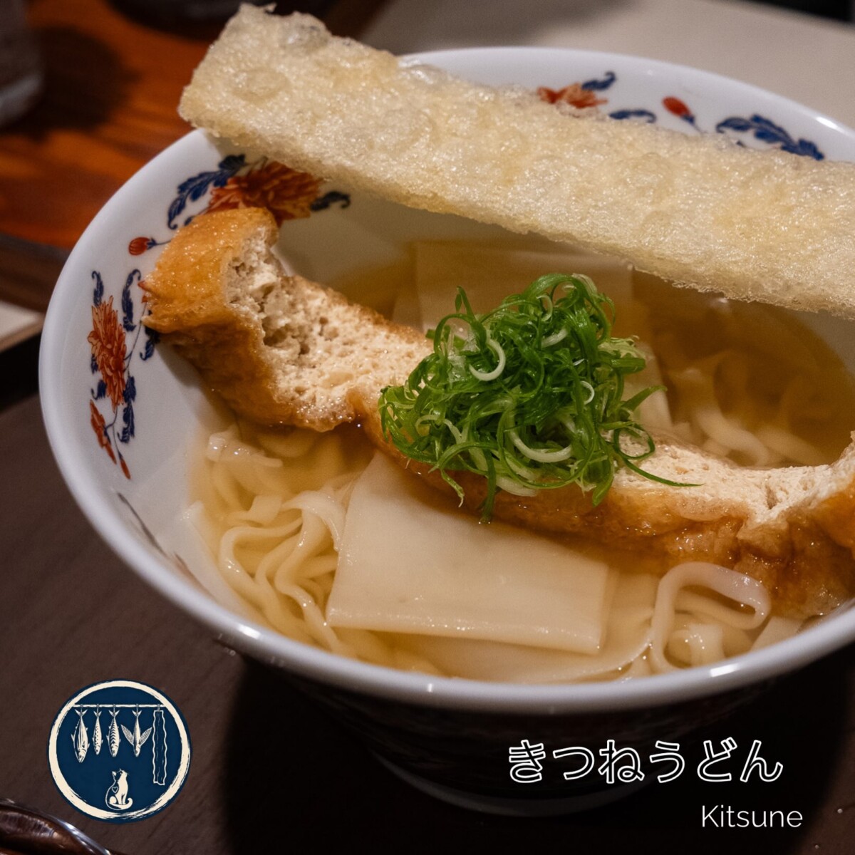 Kitsune udon with two pieces of fried beancurd, spring onion and flat noodles