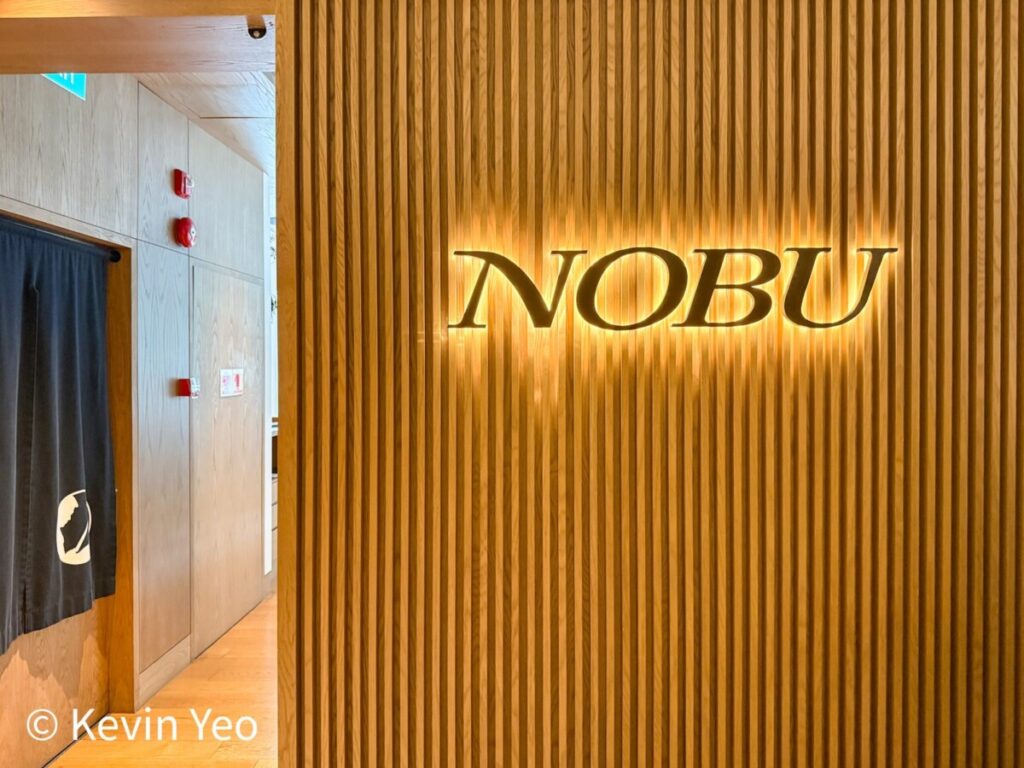 Nobu Singapore gold entrance sign on wooden slats with noren