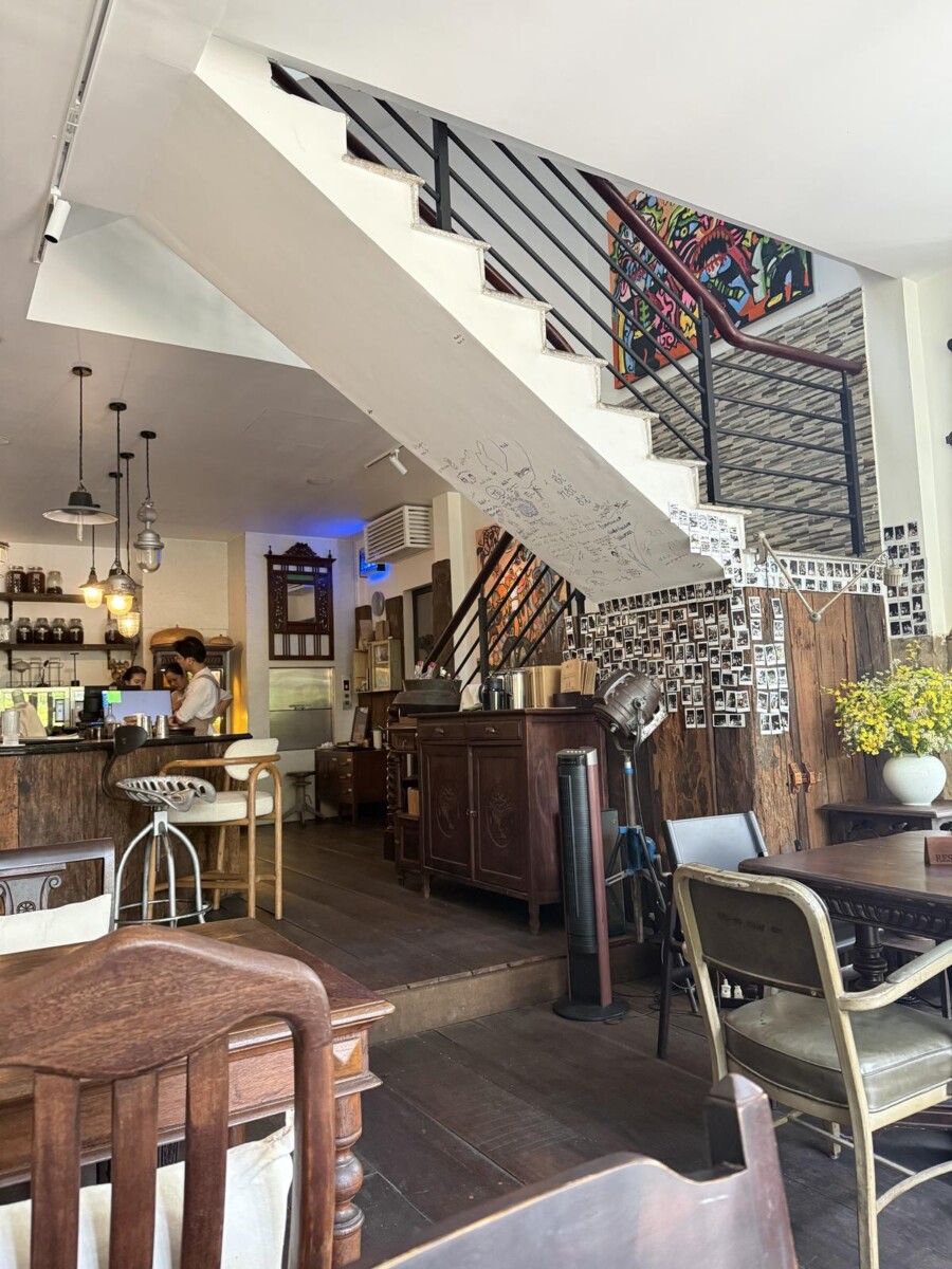 Eclectic interior of NUC Kitchen and Bar Saigon with a polaroid wall and signed scribbles under the staircase