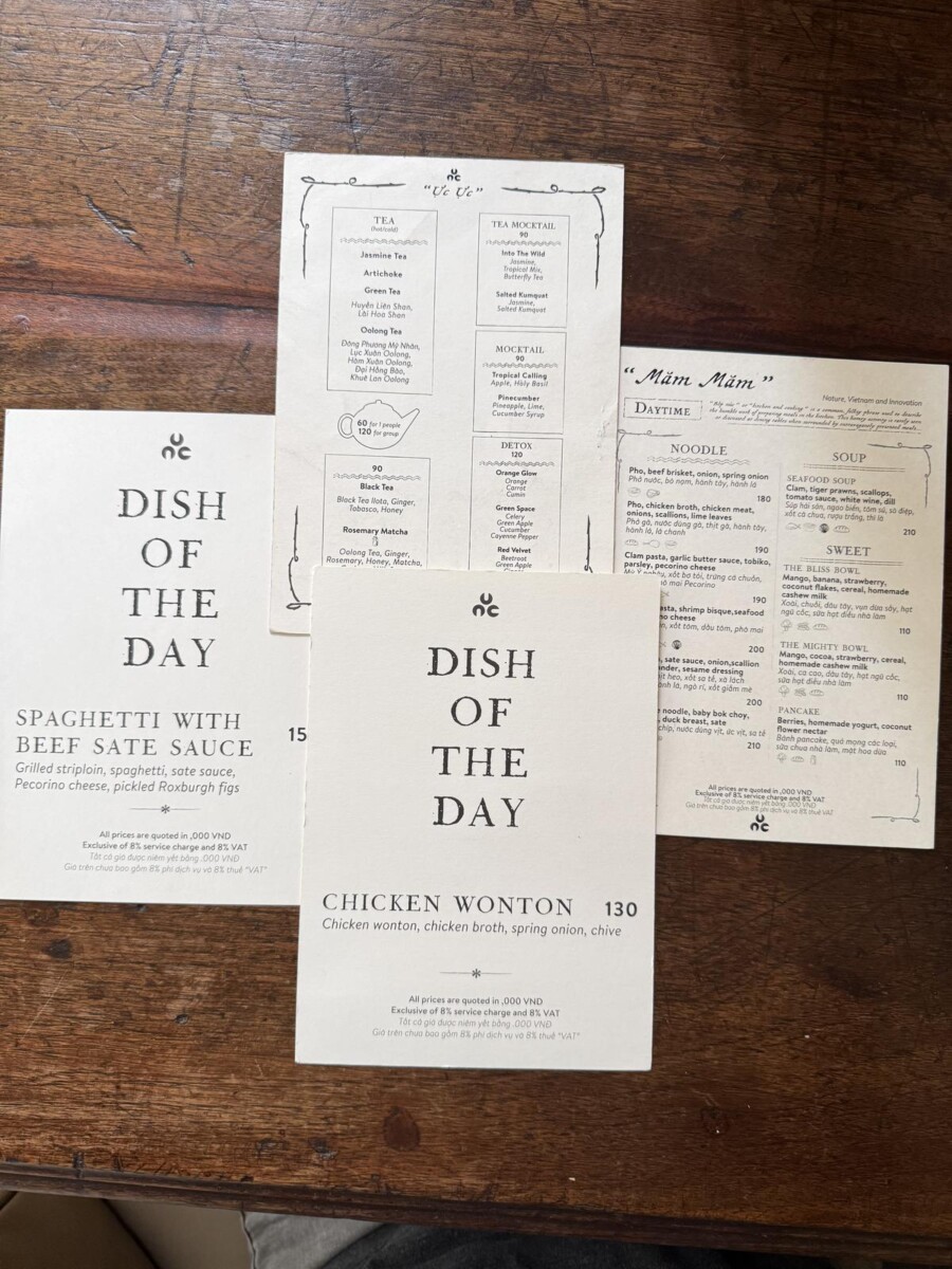 NUC Kitchen and Bar Saigon menu and dish-of-the-day cards with 8 percent service charge and VAT note