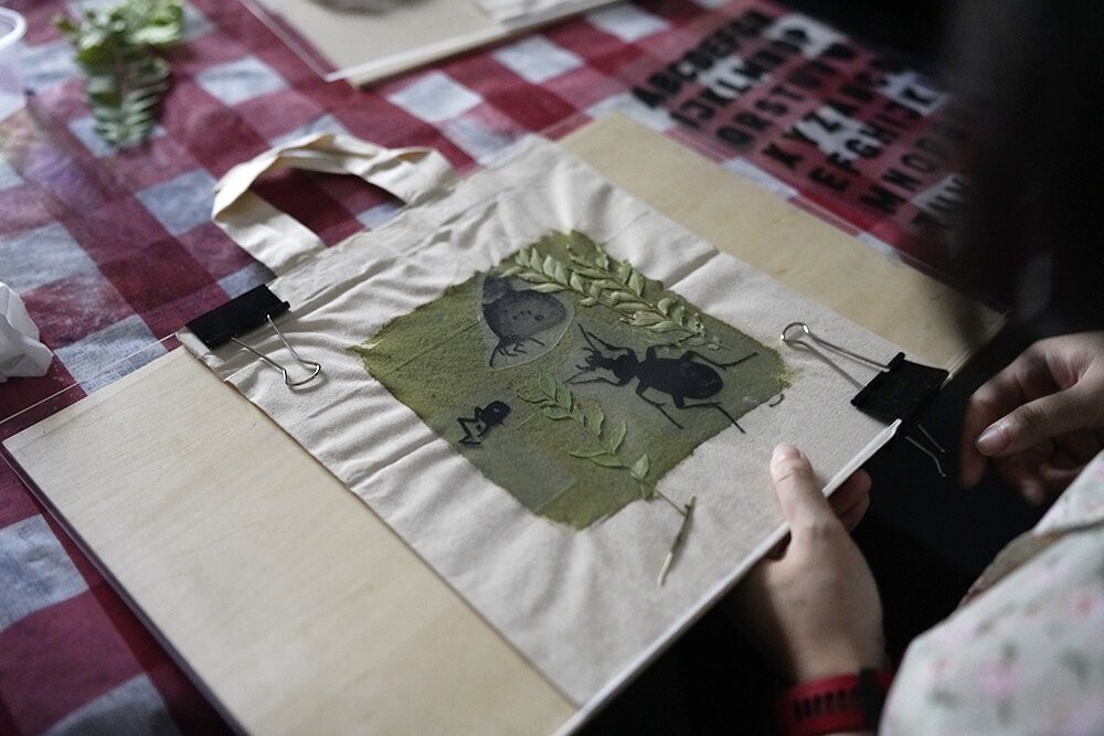 Hands arrange a cyanotype print on a table during the Objectifs Cyanotype Adventure Bag workshop