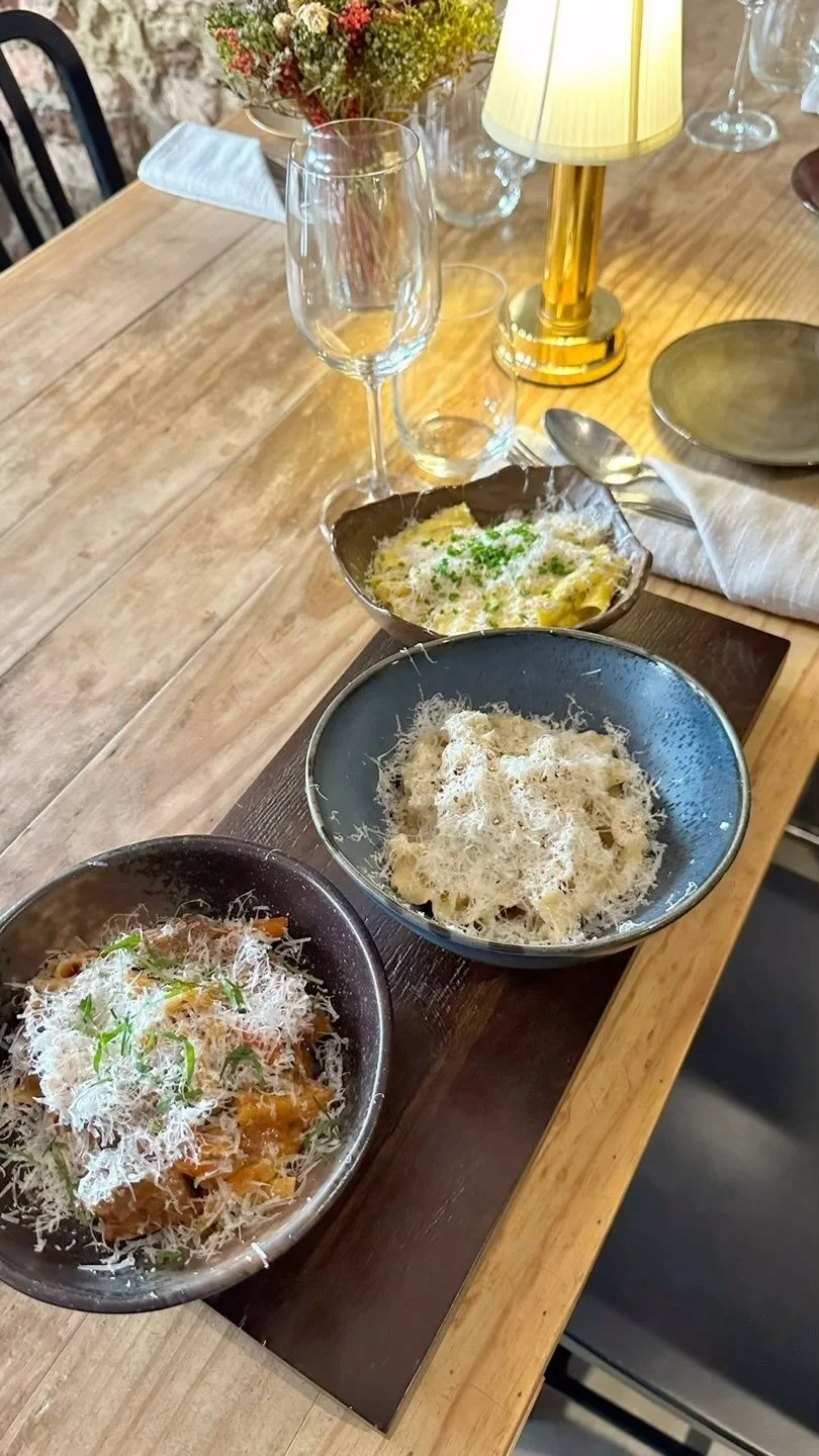 Three bowls of pasta on a wooden table at Pasta Bar