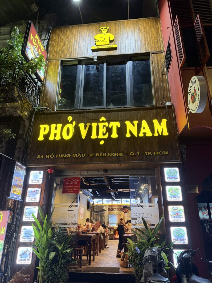 Pho Vietnam shopfront at night with a yellow neon sign in District 1, Saigon