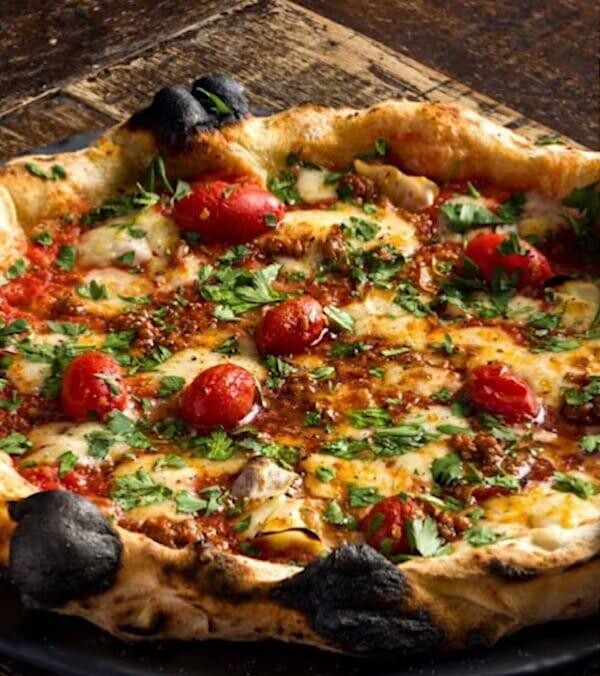 Neapolitan-style pizza with tomatoes and charred crust from PST