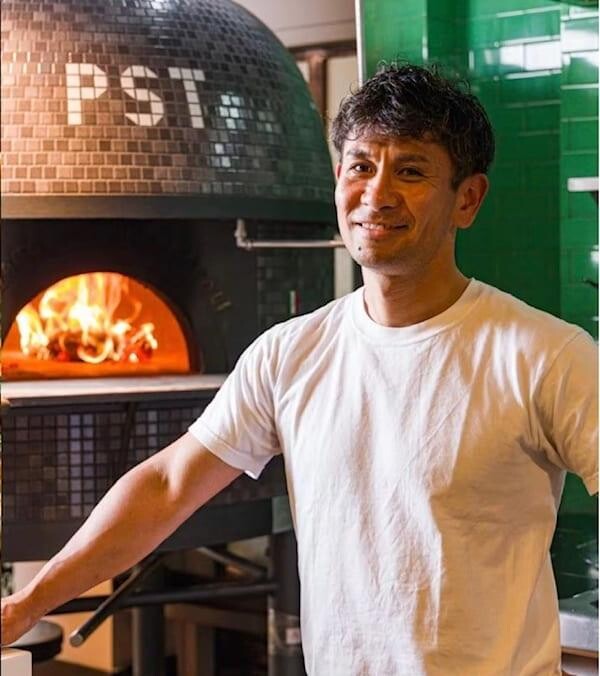 PST founder-chef Tsubasa Tamaki standing beside the PST wood-fired oven