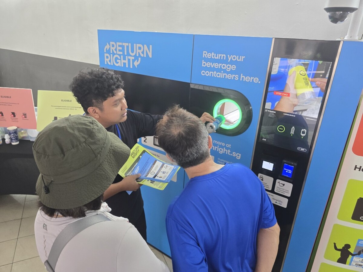 Man in a lanyard shows two residents how to insert a container into a Return Right machine