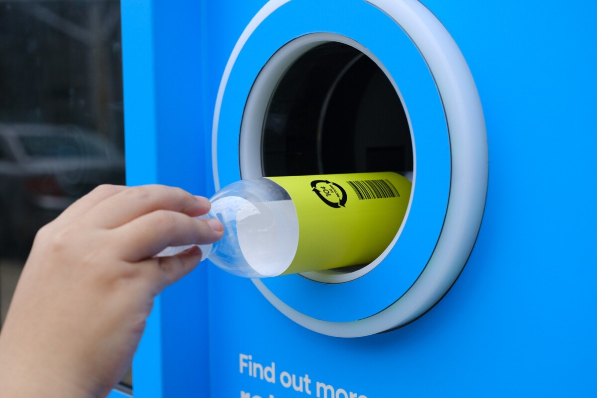 Hand inserting a plastic bottle with the 10-cent deposit mark into a Return Right machine