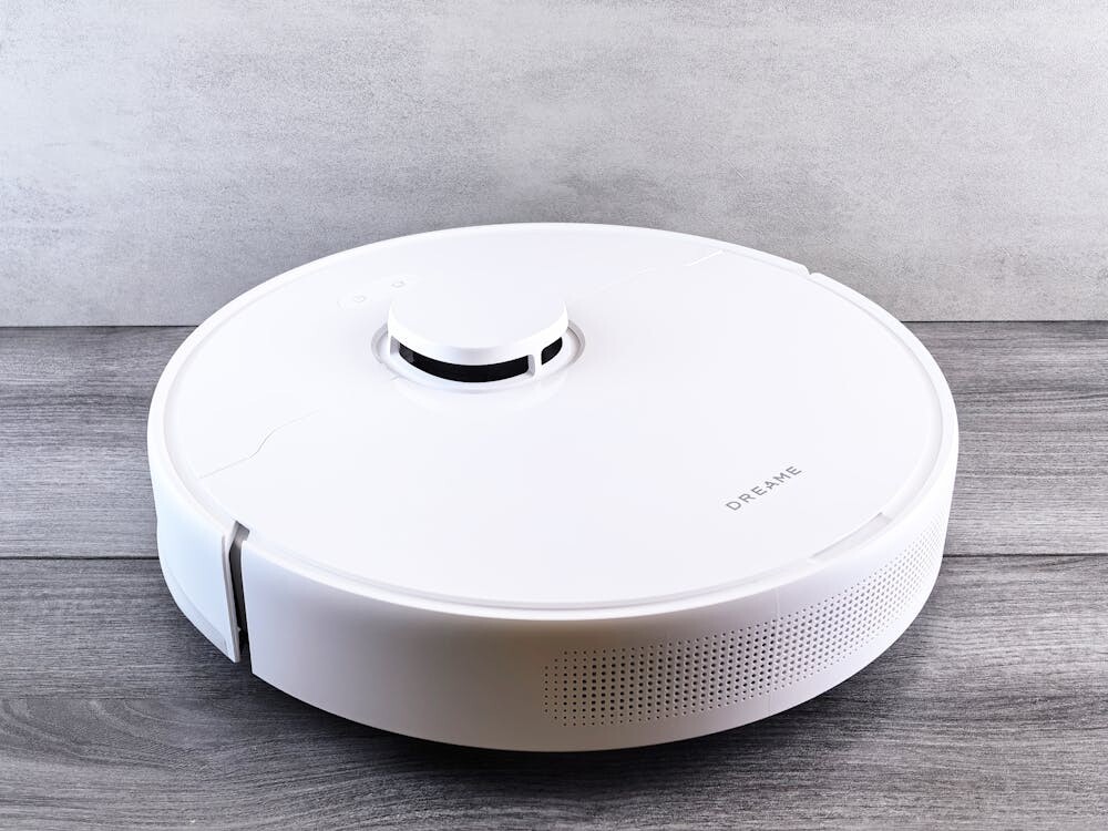 White robot vacuum cleaner on a wooden floor in a modern home