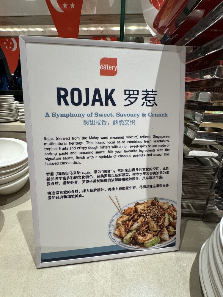 Signage at the buffet reading ROJAK, A Symphony of Sweet, Savoury and Umami, with explanatory text and a photograph of the dish
