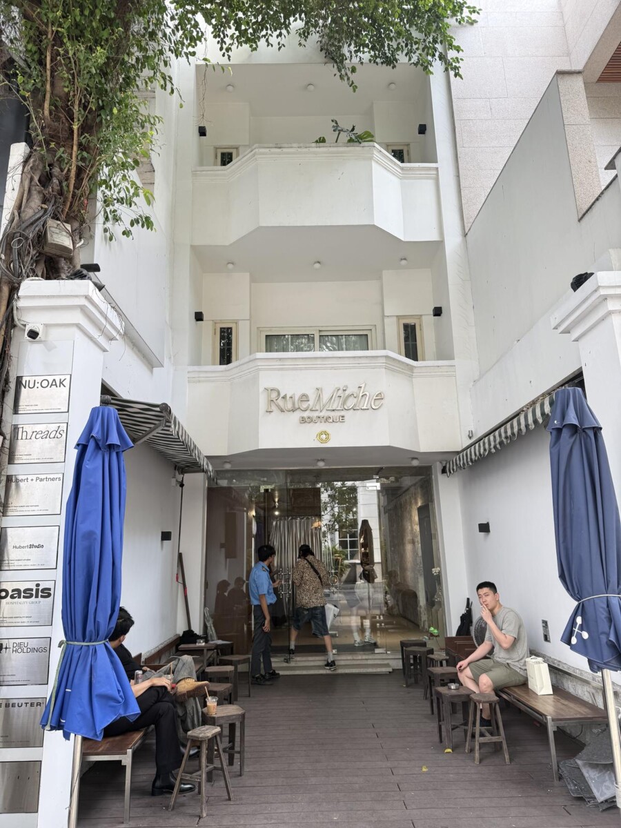 Rue Miche Boutique in Saigon, a white colonial-style building with outdoor seating in front