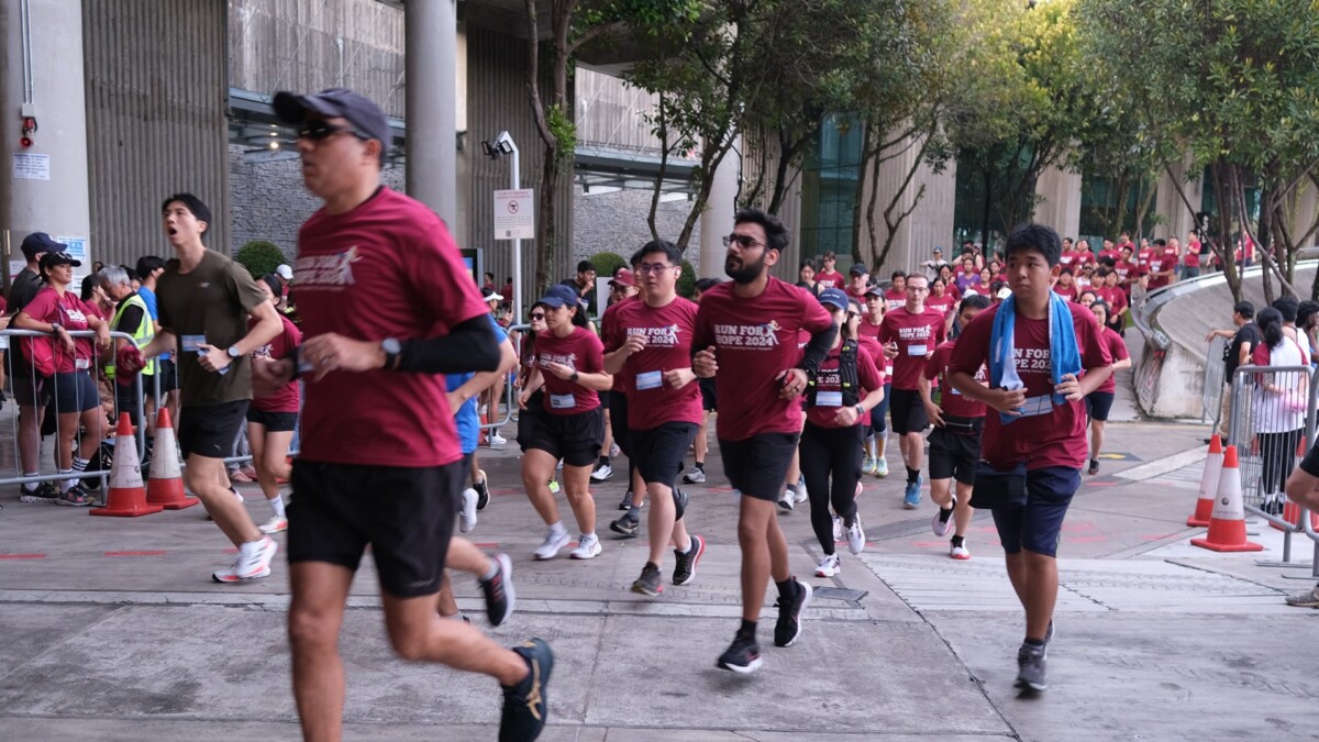 Runners in maroon Run For Hope shirts jogging along a paved path