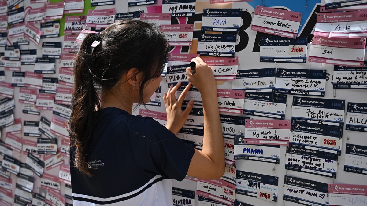 A supporter writing a dedication on the message wall at Run For Hope 2025