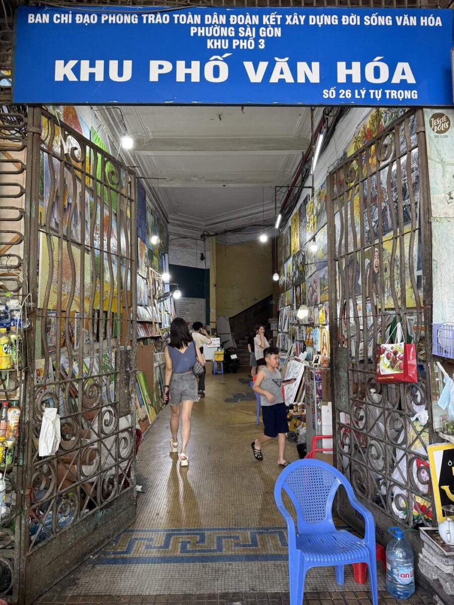 Entrance at 26 Ly Tu Trong, Saigon, narrow alleyway lined with paintings and a Khu Pho Van Hoa sign above the door