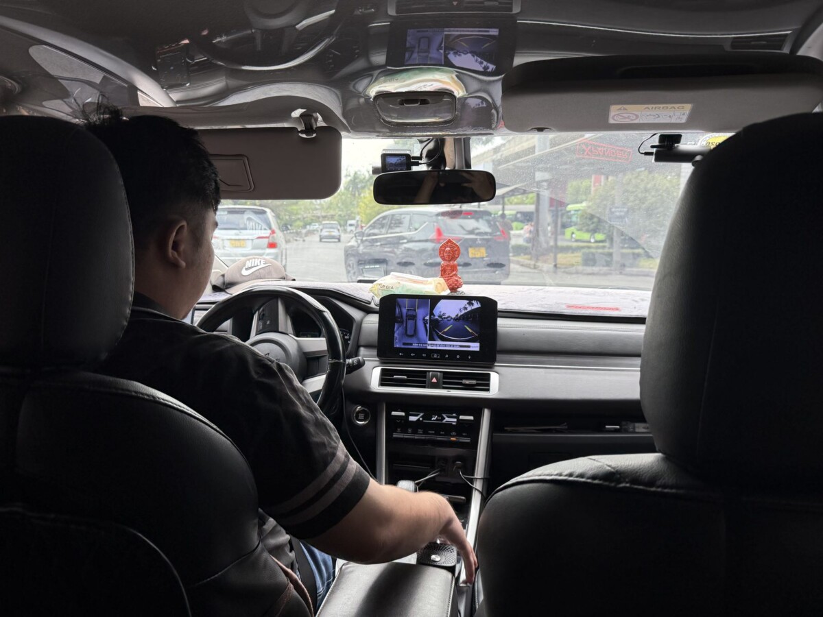 Inside a clean Klook private-transfer car in Saigon with a small Buddha figurine on the dashboard
