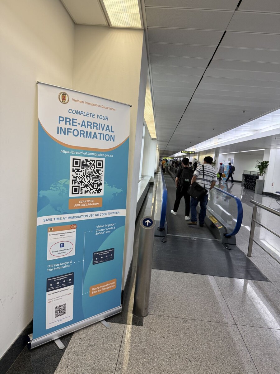 QR code banner for the Vietnam e-arrival form at Saigon airport, mounted along the travelator on the way to immigration