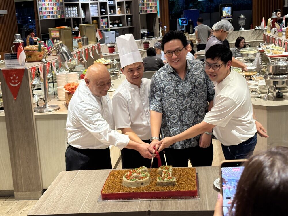Two chefs and two guests cutting the 61 carrot cake together while attendees photograph the moment on their phones