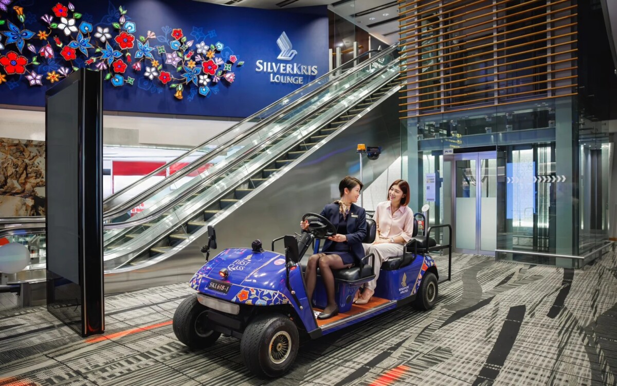 Singapore Airlines staff drive two First Class passengers in a buggy past the SilverKris Lounge at Changi Airport