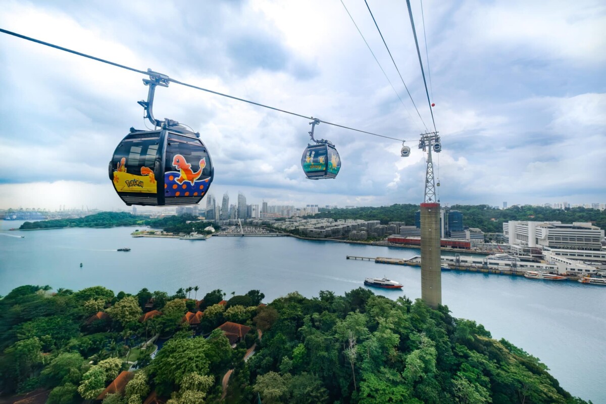 Pokémon-themed Singapore Cable Car cabin with Charmander artwork above the harbour and Sentosa
