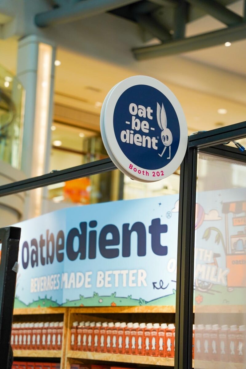 Oatbedient oat milk exhibitor booth 202 at Singapore Coffee Week with shelves of bottled drinks