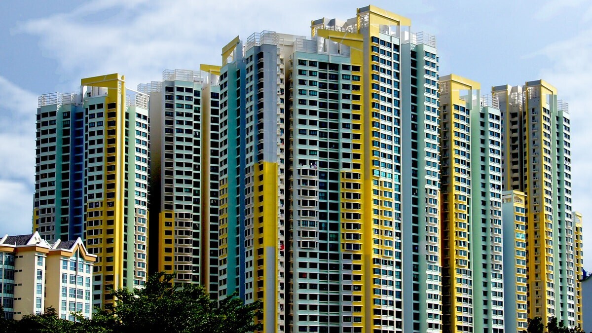 Cluster of modern HDB towers with blue and yellow facade under cloudy sky