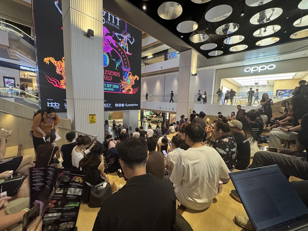 Media and content creators seated on the floor of a mall atrium in front of a large Singapore Night Festival 2026 promotional screen