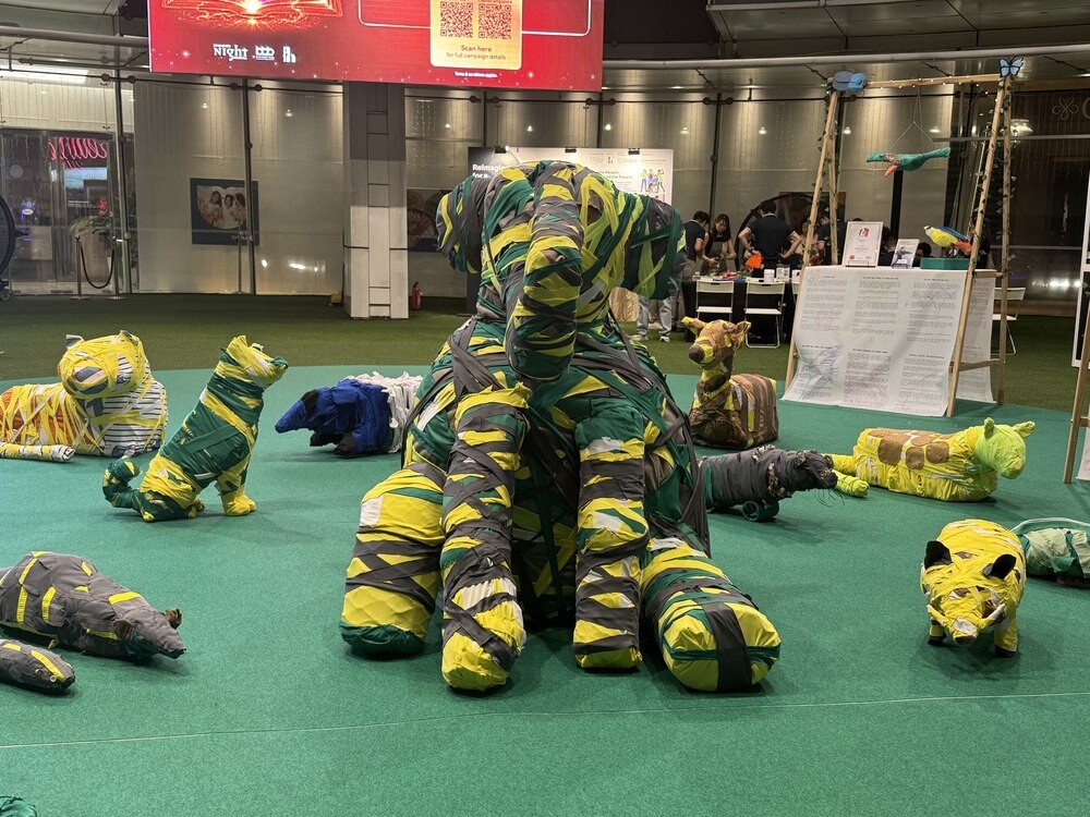Life-sized animal sculptures, including an elephant, made from wrapped yellow, green and grey fabric strips, displayed on artificial turf at Capitol Singapore Outdoor Plaza