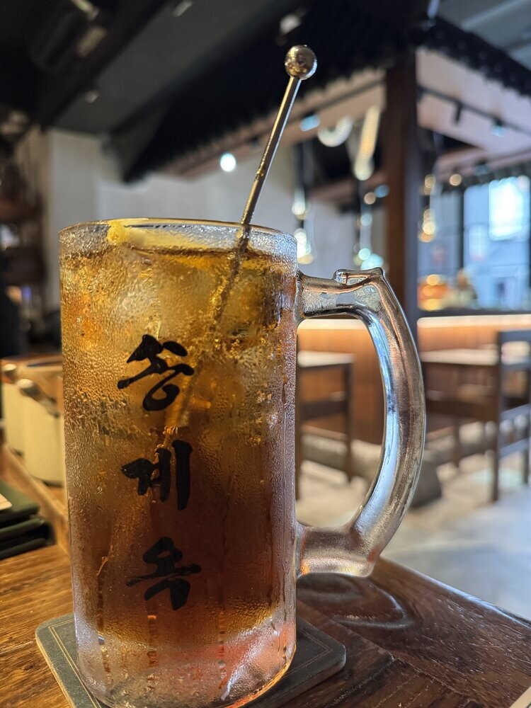 A frosted glass mug of Earl Grey Highball cocktail with visible condensation, resting on a wooden table