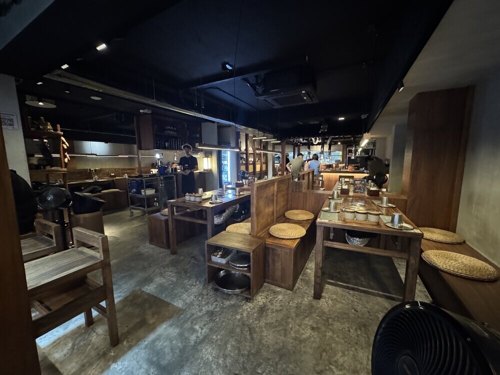 Interior of Song Gye Ok showing wooden bench seating with round straw cushions and low tables around a central grill station