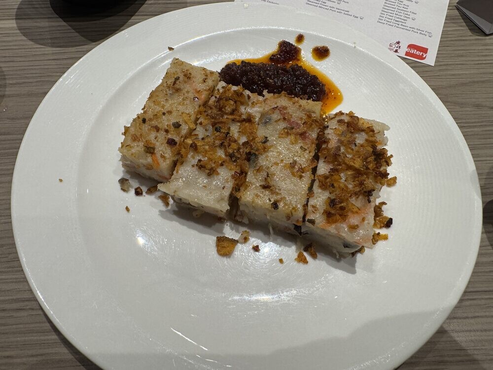 Plate of sliced steamed carrot cake topped with dark sauce and preserved radish