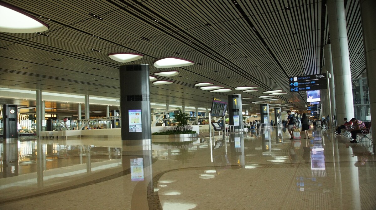 Departure hall of Changi Airport Terminal 4 with check-in row signs and travellers with luggage