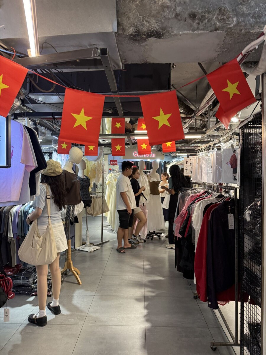 Inside the basement of The New Playground in Saigon, racks of clothing and Vietnamese flags overhead