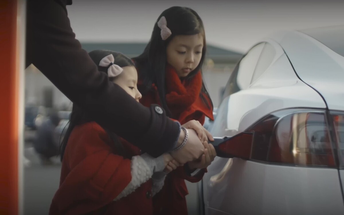 Family plugging a Tesla Supercharger connector into a Tesla car