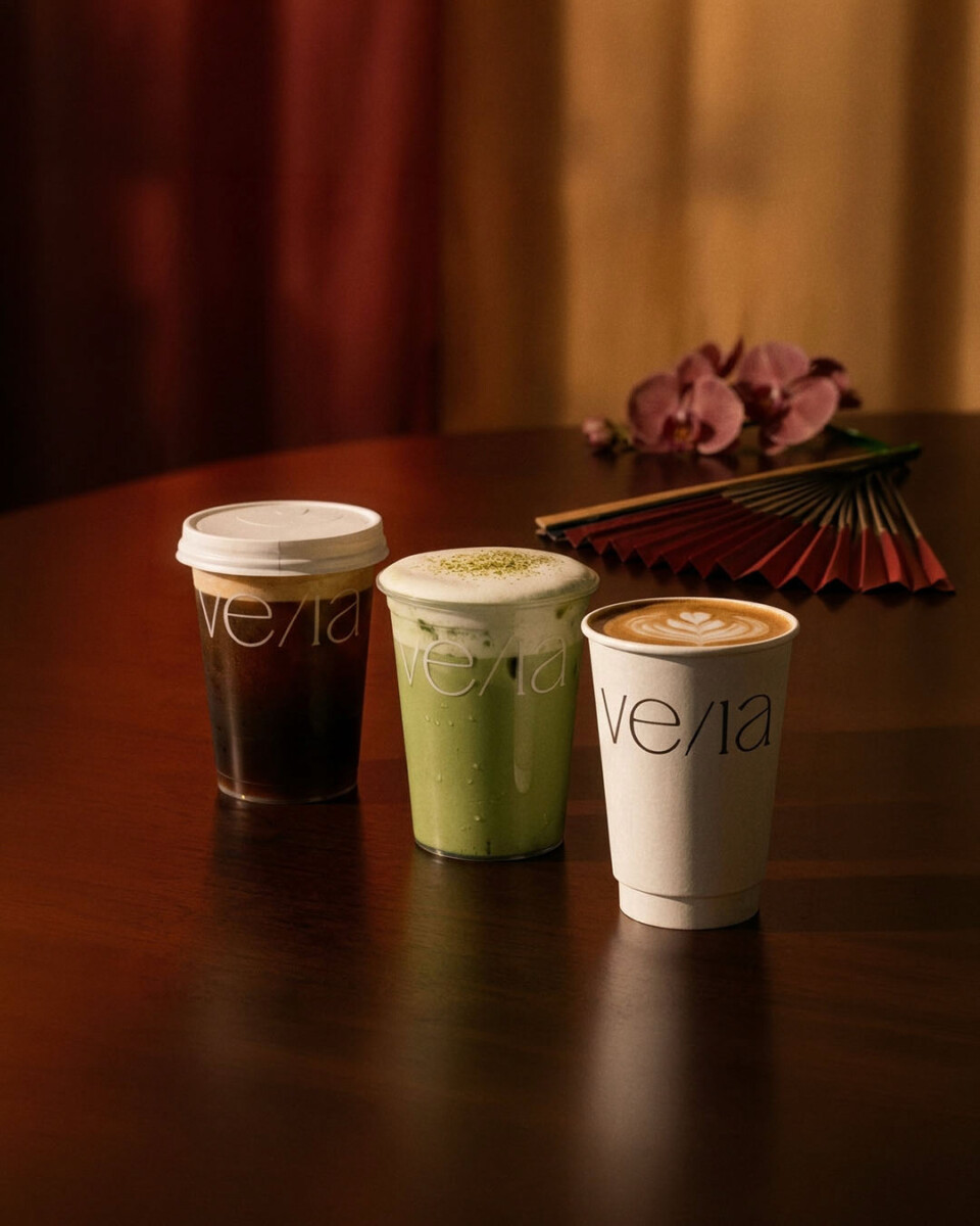 VE/LA iced coffee, iced matcha latte and hot latte in branded cups on a wooden table