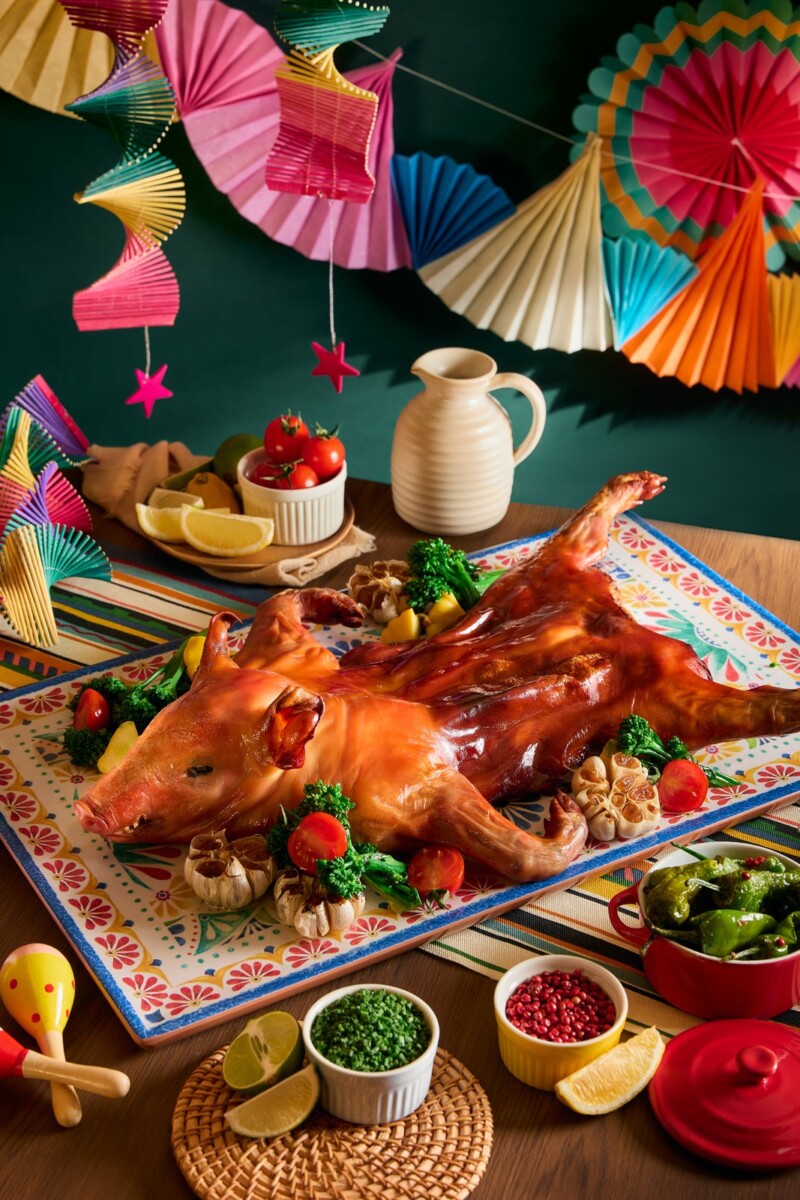 Whole roasted Spanish suckling pig on a patterned platter with patatas bravas at Verandah