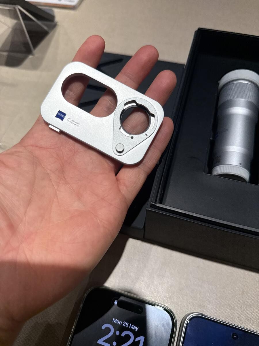 Holding the vivo ZEISS Telephoto Extender mount adapter to show its compact palm-sized design